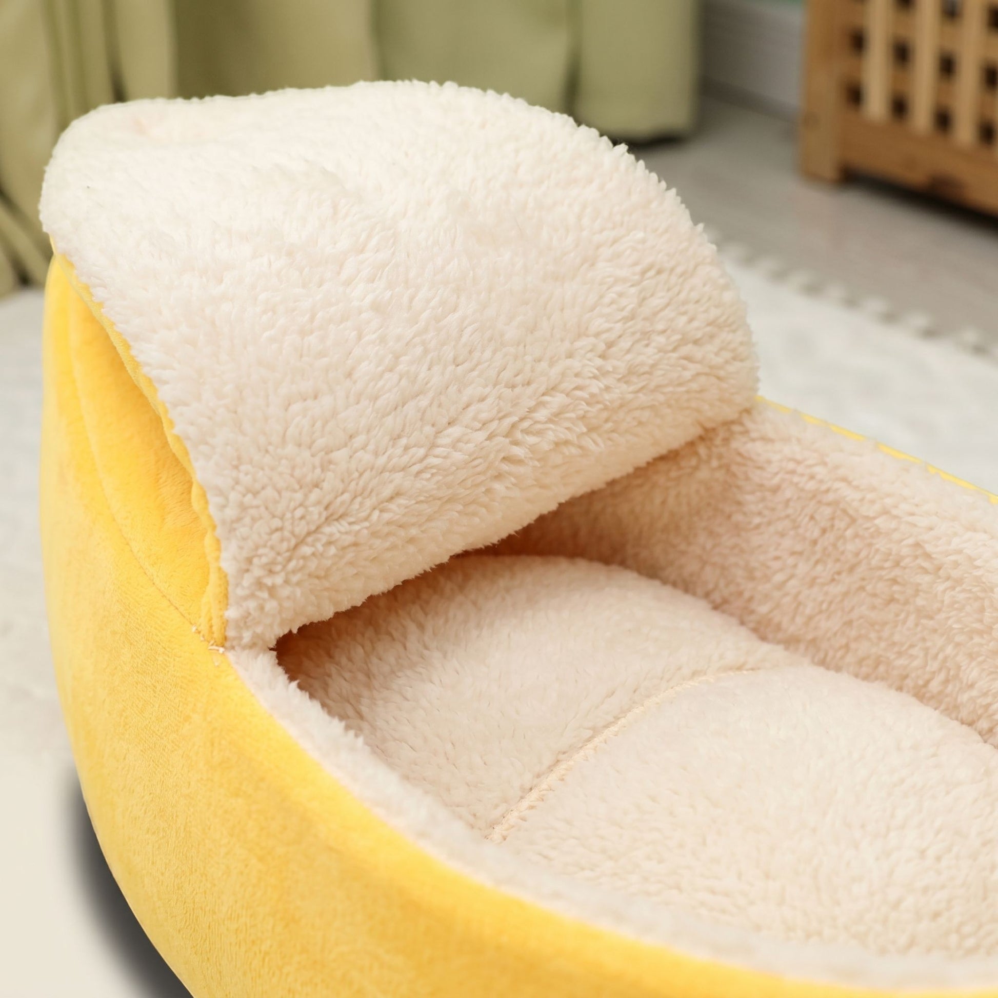 Close-up of plush interior and stitching detail of banana-shaped cat bed, emphasizing warmth and comfort.